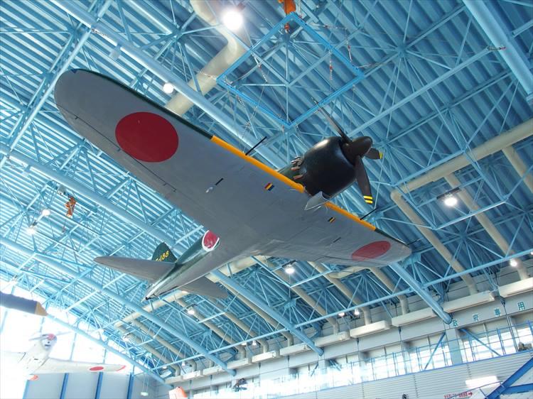 「展示格納庫」の中空に展示されている零式艦上戦闘機（俗にいうゼロ戦）の五十二型43-188号機。昭和38年にグアム島で発見され、日本へ返還されたのちに復元された機体だ。