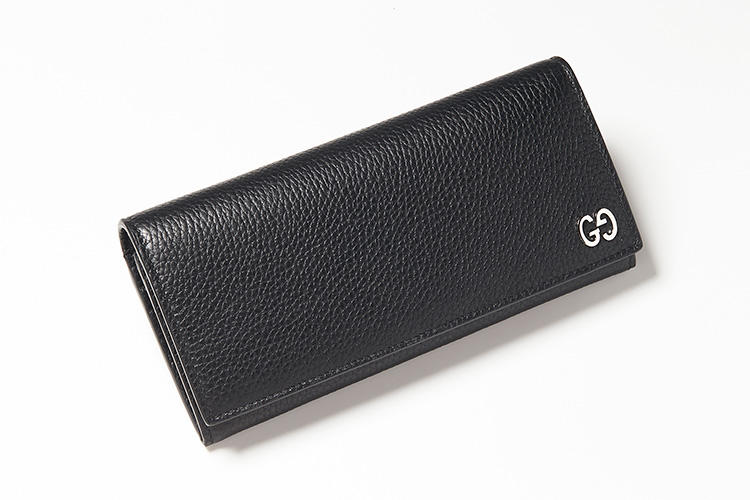 <strong>GUCCI／グッチ</strong><br />シボ革のロングウォレットは柔らかく手触りのよい質感。これまでジャカードや型押し、プリント柄などで見られた「GG」ロゴをメタルピースであしらいにさりげなく高級感とブランドの品種が漂う。背面にもチケットポケットが配されている。縦9.5×横19×マチ3cm。8万2000円（グッチ ジャパン）