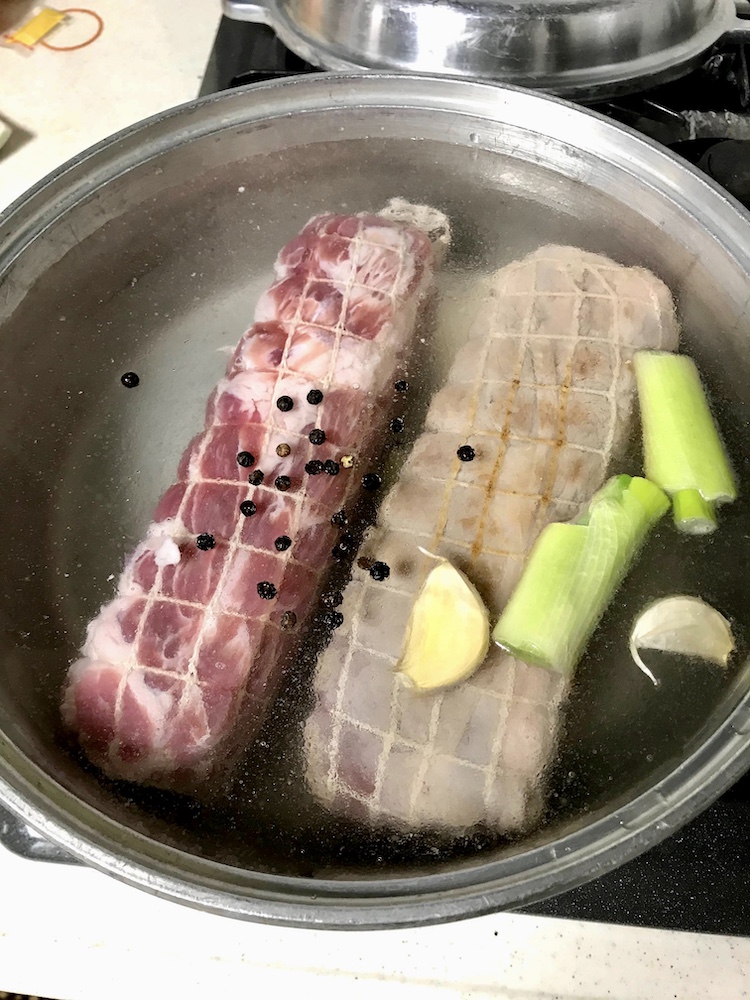 <p>4.先程の肉を鍋に入れ、水を肉が完全に被るまで入れる。ネギの青い部分、生姜、ニンニクと酒50cc、黒胡椒粒を入れ火にかける。</p>
