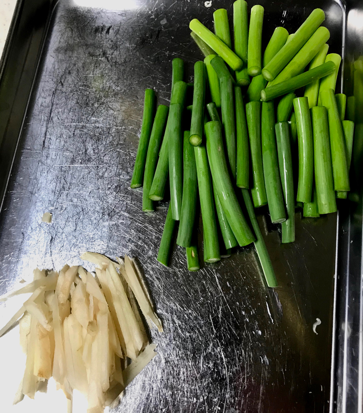 <p>4. その間に、野菜の下処理。生姜は千切りにしておく。ニンニクの芽は根元の固い部分を切り落とし、4cmの長さに切る。</p>
