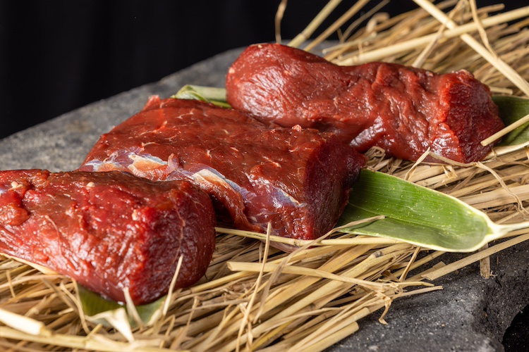 <p>特に鹿肉は、信州が誇る熟練の猟師がこだわりを持った方法で処理をした特別なジビエ。急所への一発で仕留めた鹿を、捕獲後すぐに解体処理を現地にて行い、-60℃で急速冷凍することで、クセの元となる臭みを極限まで抑え、鹿肉本来の旨味を引き出している。</p>
