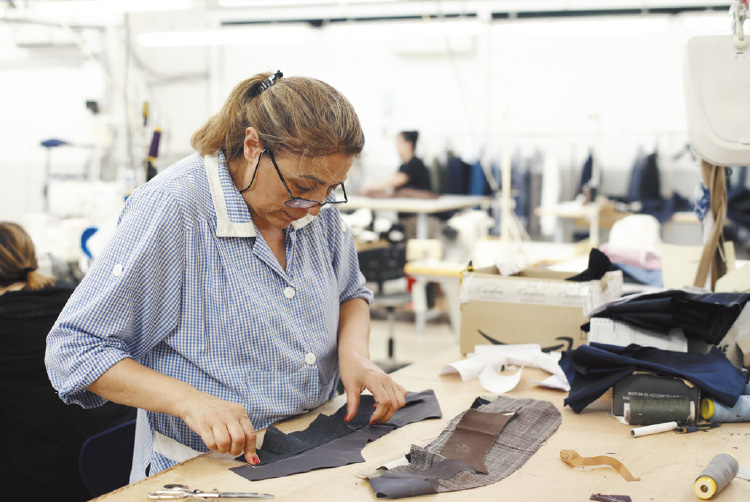 襟の芯地を生地の上に正確に配置し、その後に襟の形を整えて、最終的にジャケットに取り付けるための重要な工程