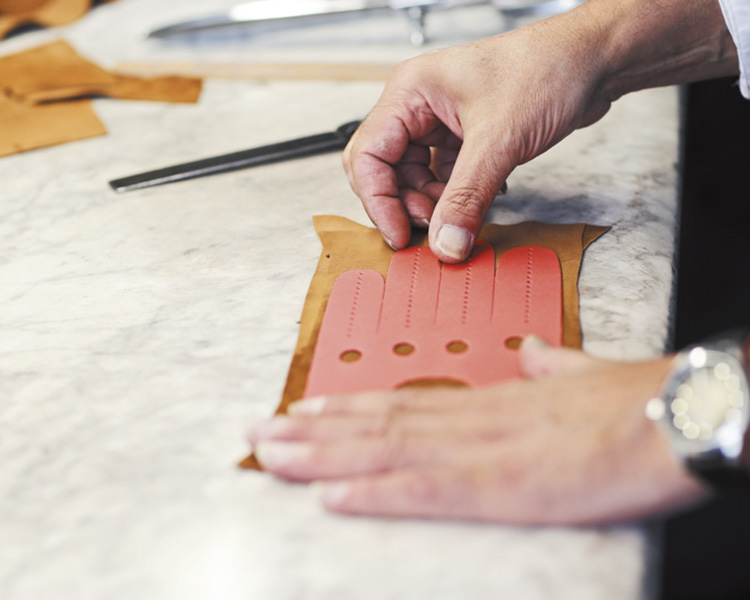 繊細な手の感覚で革の伸びや厚みを確かめながら型紙を置く